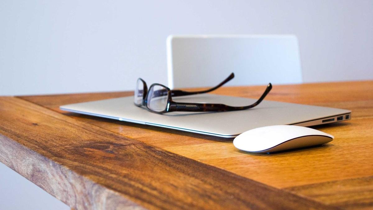 Laptop, glasses and mouse on a desk
